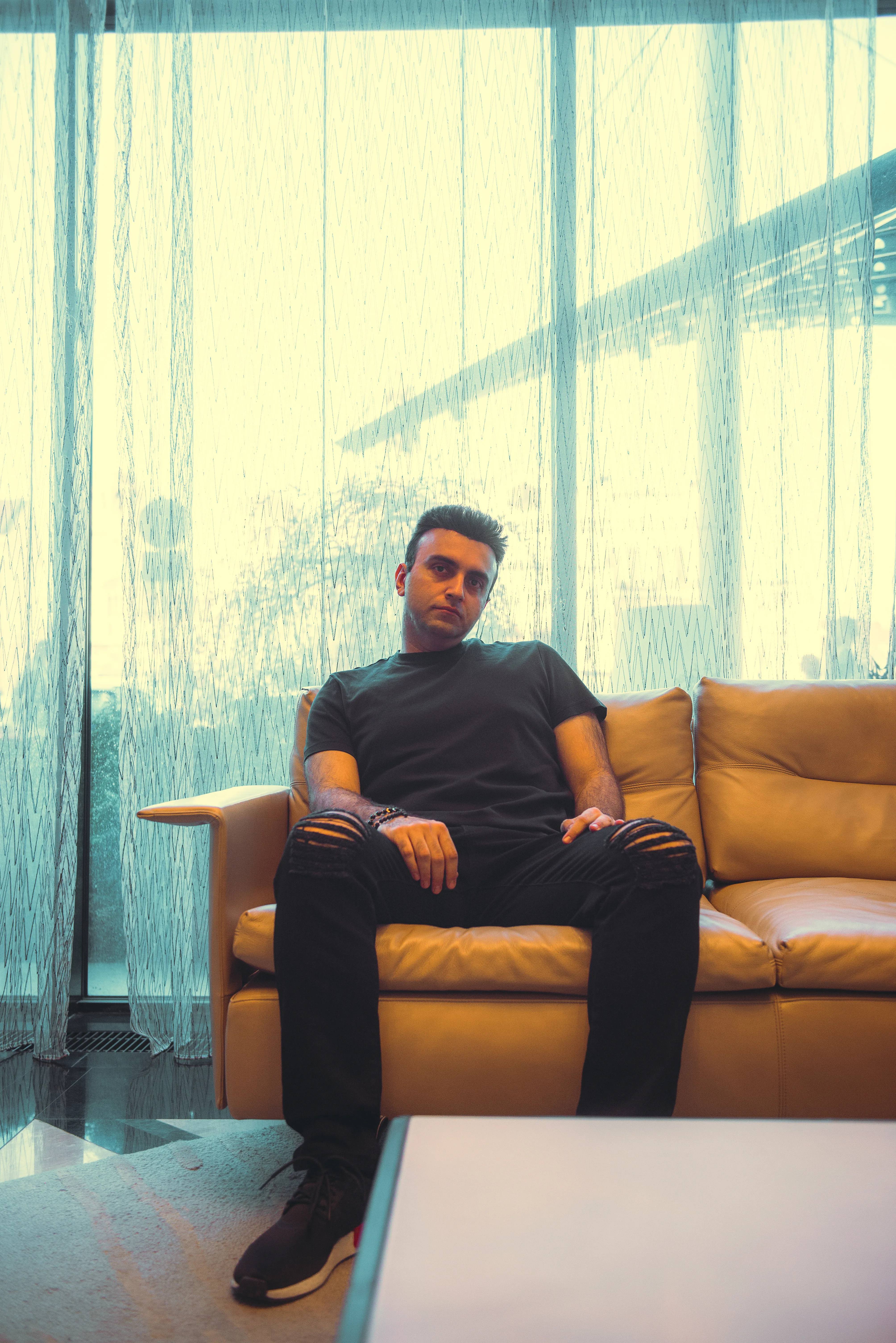 Taha Asadi seated on a couch, looking into the camera