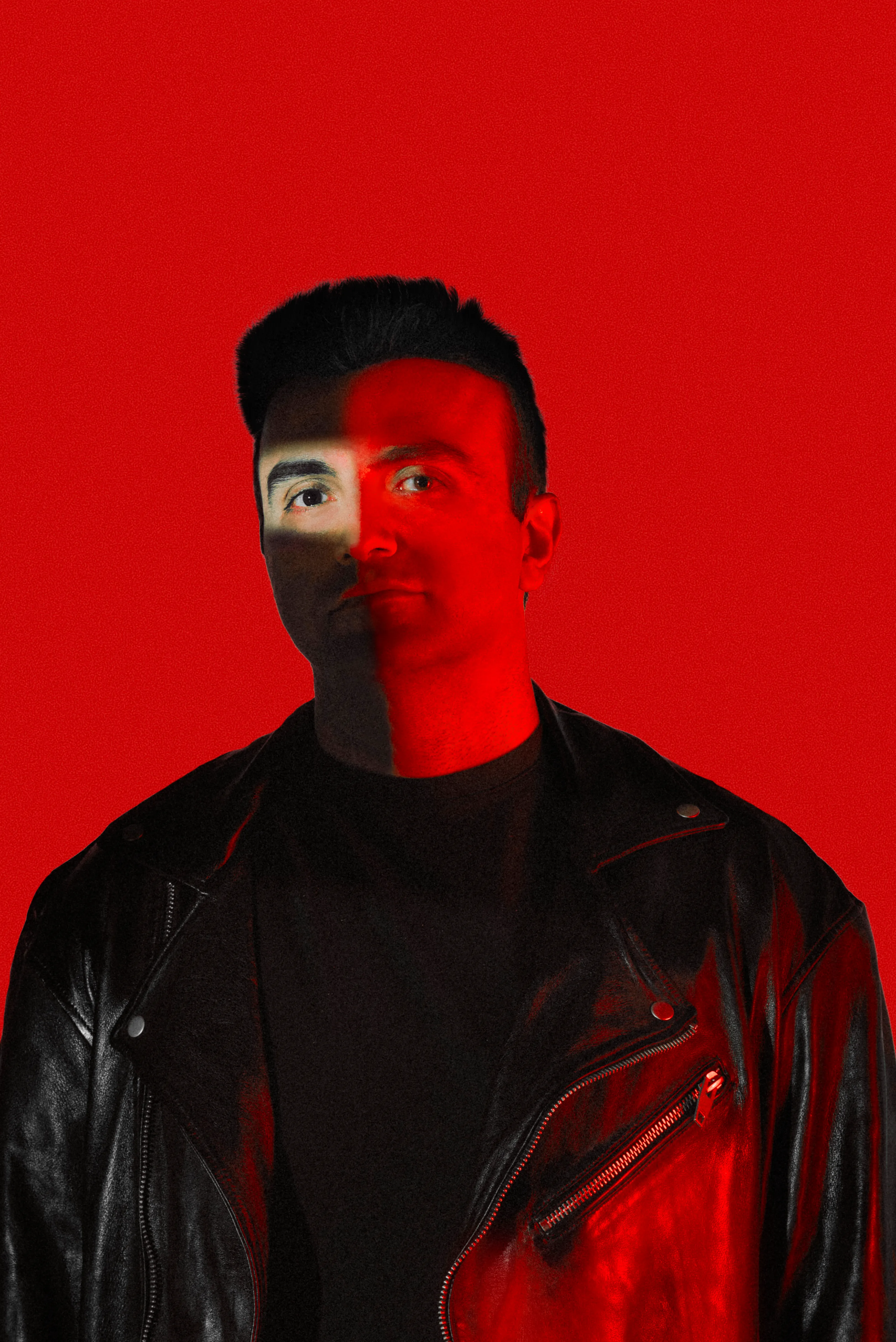 Red-lit artist portrait of Taha Asadi in a leather jacket, half his face in shadow